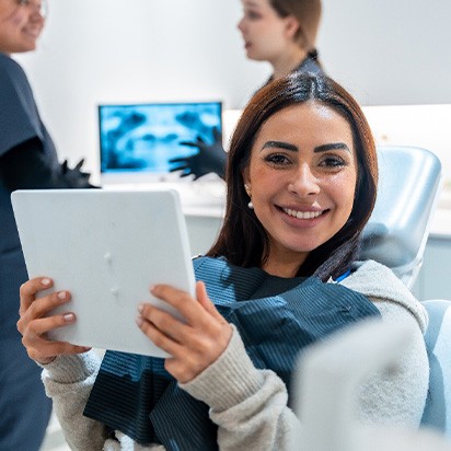 Woman smiling while holding handheld mirror