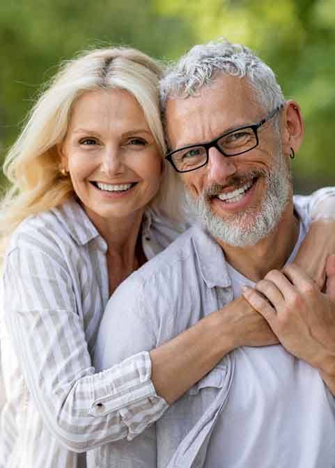Senior woman hugging senior man from behind