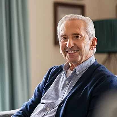 Senior man sitting on couch smiling