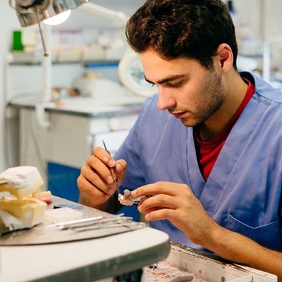 Dentist pulling a dental crown from a model