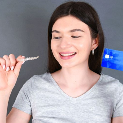 Woman holding payment card and Invisalign aligner